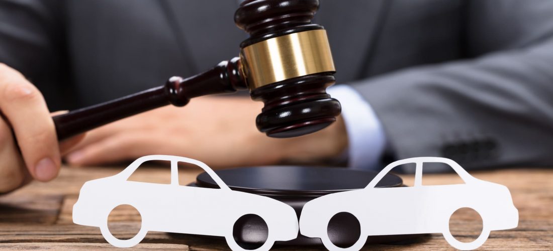 Judge And Car Damage Appraisal Midsection of judge hitting mallet by paper cars on wooden table